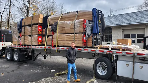 A person standing beside a truck loaded with packaged lift equipment